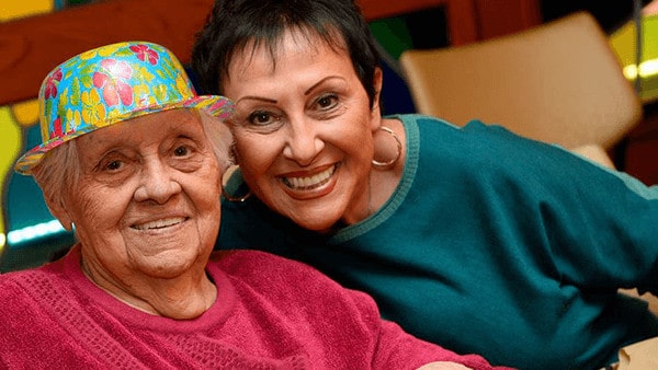 Elderly Woman Patient in Flower Hat Smiling with Middle Aged Woman