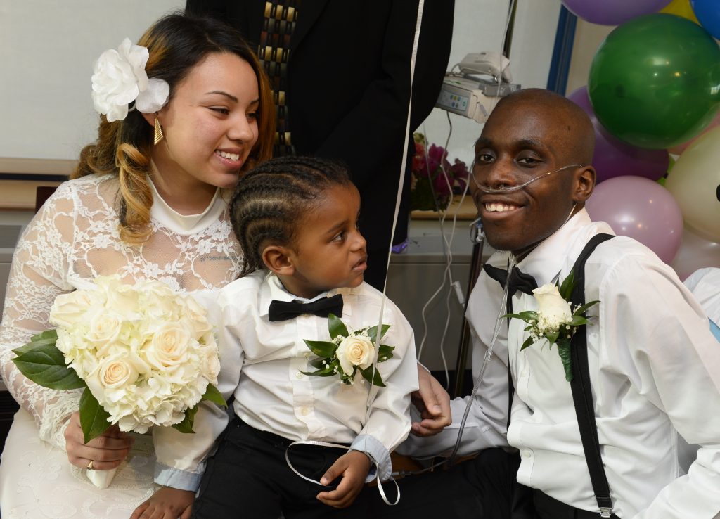 Bride and Patient Groom Seated Holding Son at Hospital Wedding