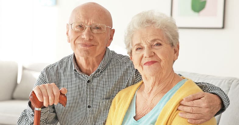 Older couple hugging and smiling in their living room