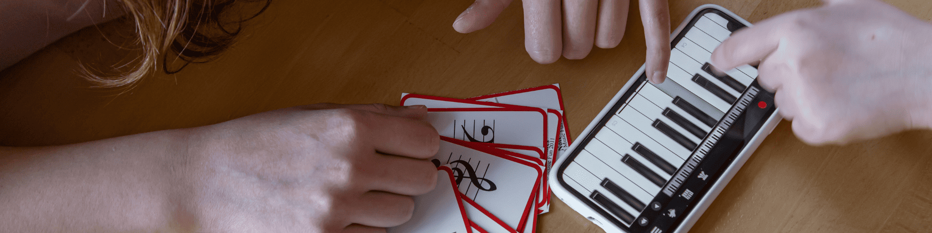 two people playing piano keys on phone