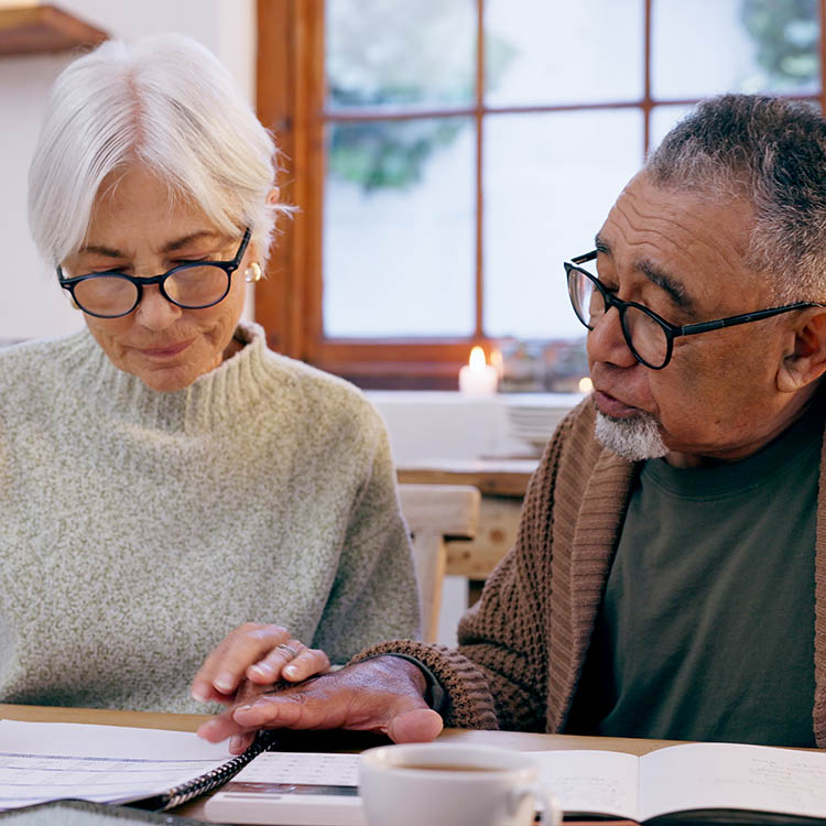 A couple sits at a wooden table reviewing a legal document together.
