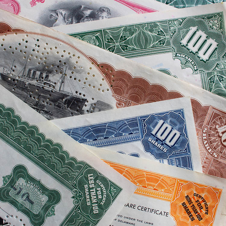 Close-up of overlapping vintage stock certificates with decorative borders and 